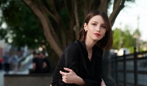 Woman with a slicked-back neck-length bob wearing pearl earrings